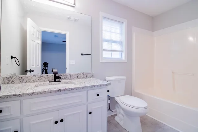 a bathroom with a granite countertop toilet sink and mirror
