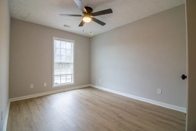 an empty room with wooden floor and windows