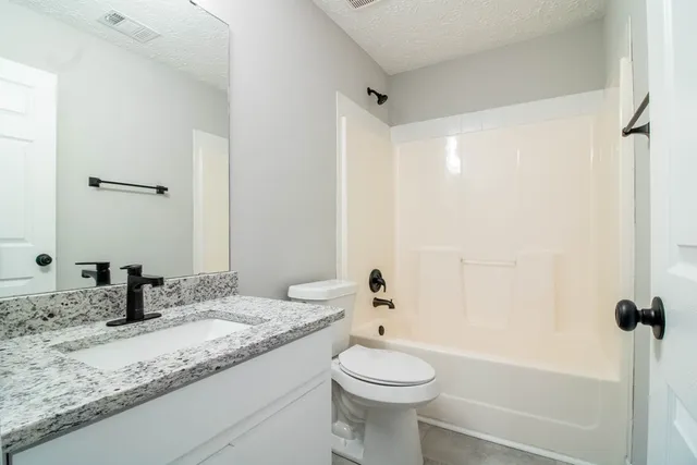a bathroom with a granite countertop sink mirror vanity and toilet