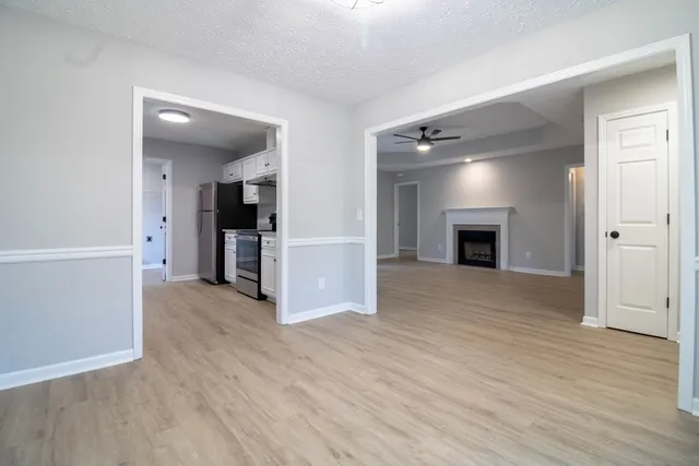 an empty room with wooden floor and a kitchen
