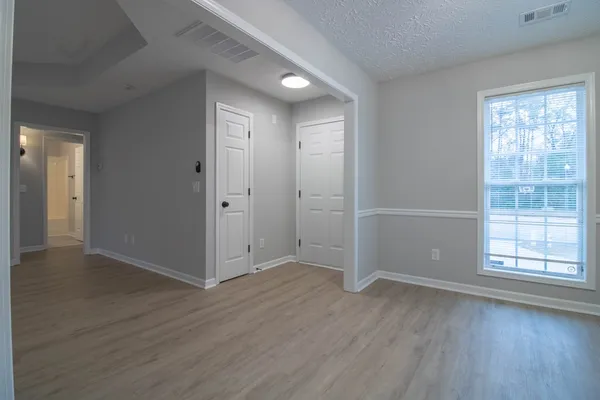 an empty room with wooden floor and windows