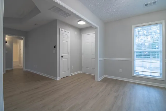 an empty room with wooden floor and windows