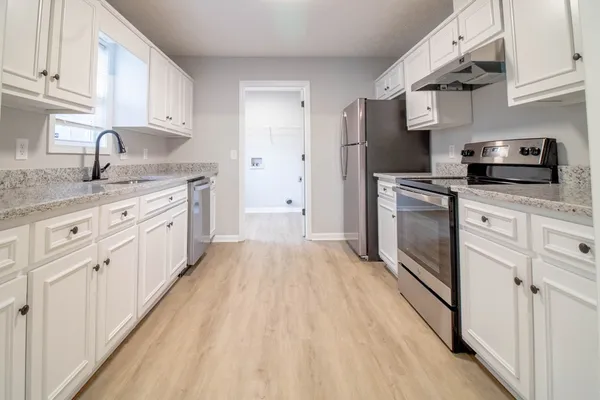 a kitchen with granite countertop a sink stove and refrigerator
