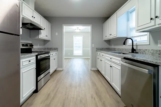 a kitchen with stainless steel appliances granite countertop wooden cabinets a sink and a stove