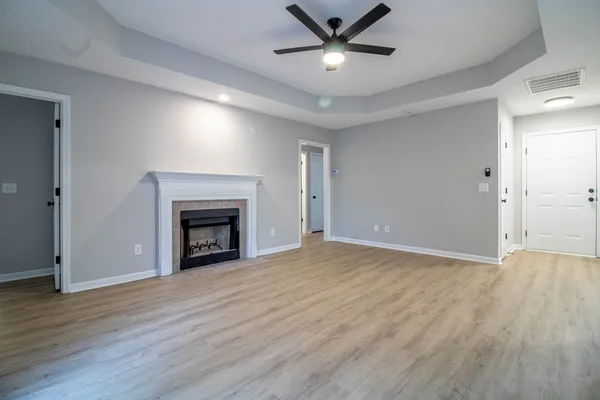 a view of an empty room with wooden floor fireplace and a window