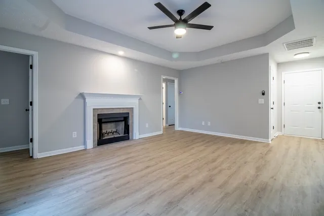 a view of an empty room with wooden floor fireplace and a window