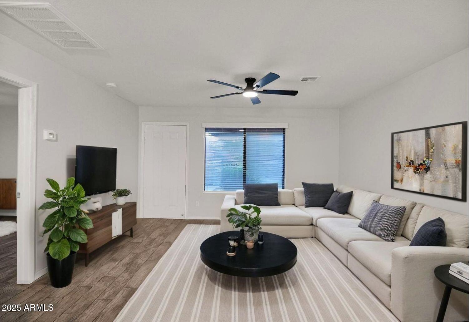 a living room with furniture a potted plant and a flat screen tv
