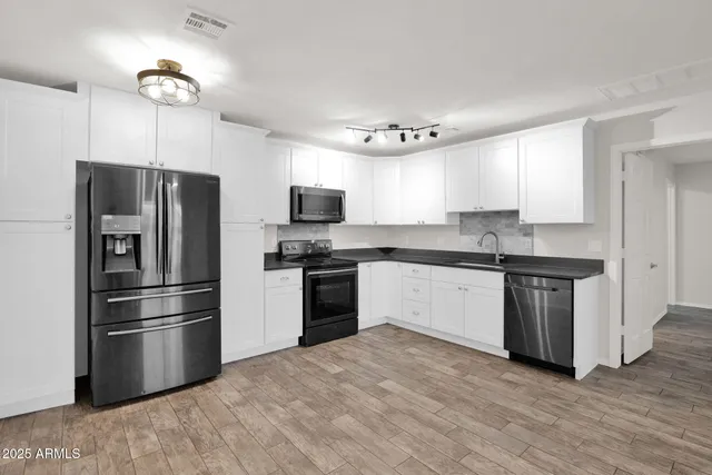 a kitchen with granite countertop a refrigerator stove and microwave