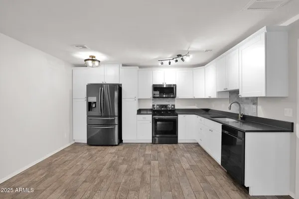 a kitchen with a refrigerator cabinets and wooden floor