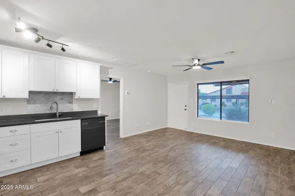 a kitchen with granite countertop a stove a sink and white cabinets with wooden floor