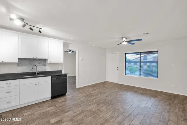 a kitchen with granite countertop a stove a sink and white cabinets with wooden floor