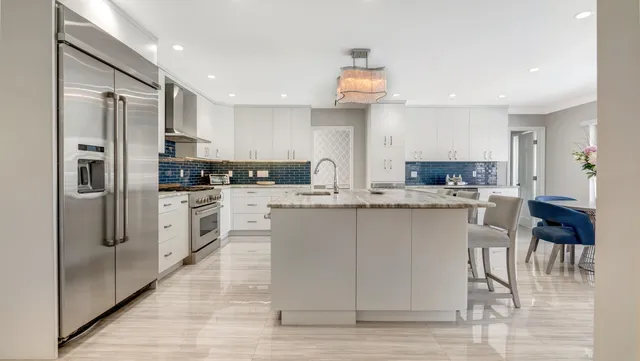 a kitchen with stainless steel appliances kitchen island granite countertop a kitchen island and chairs in it