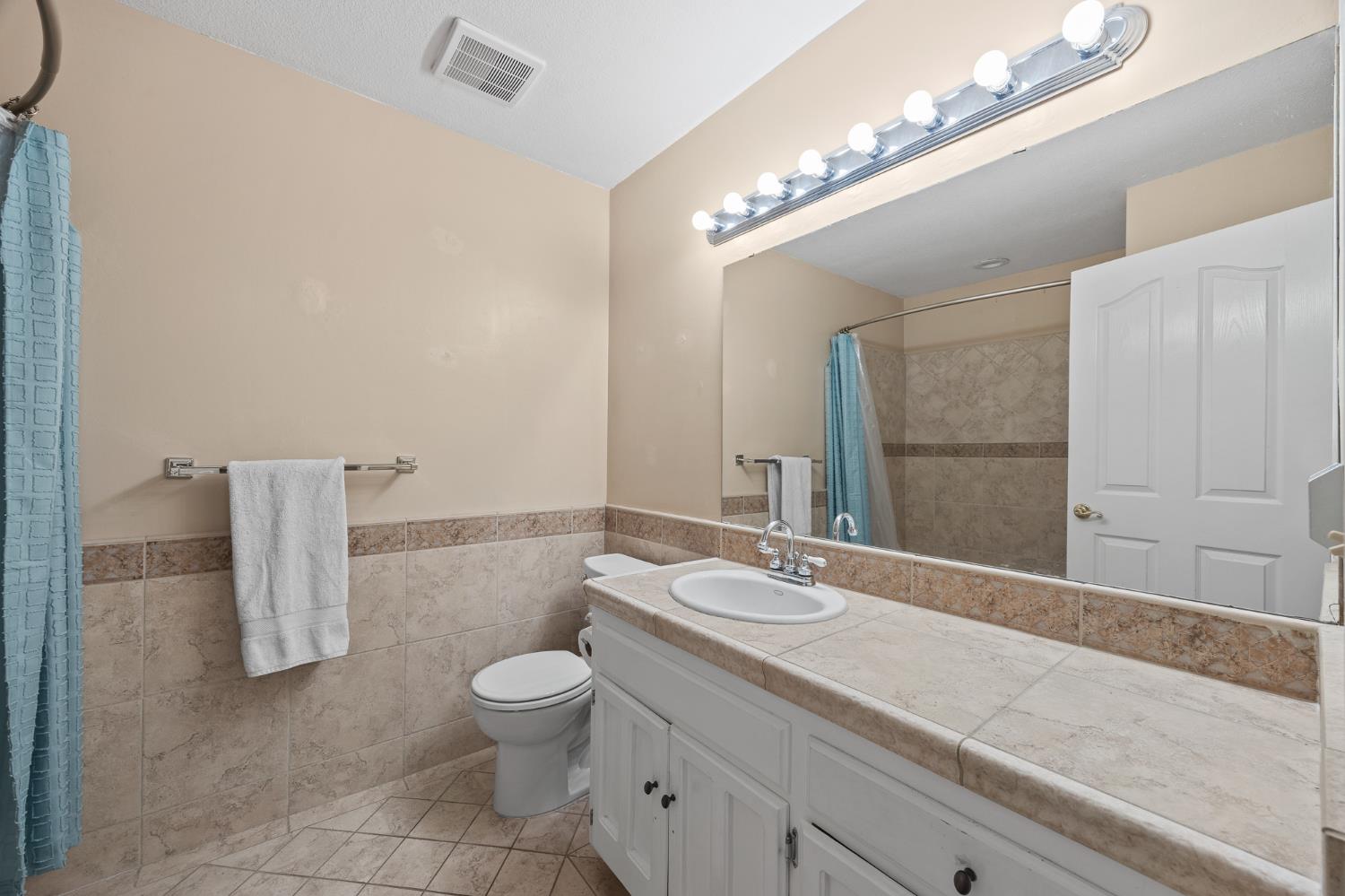 2179 Rall Avenue Clovis, CA 93611 - Photo 25 of 54 a bathroom with a granite countertop sink a toilet and a mirror