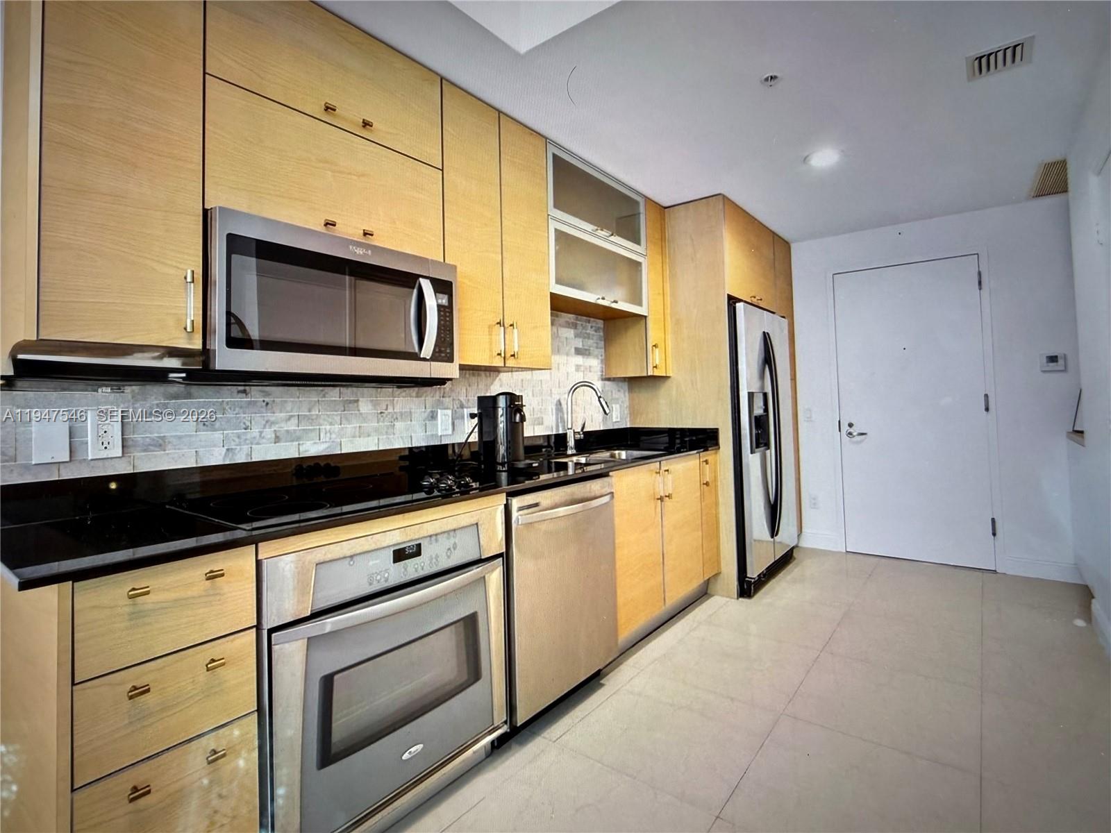 60 Southwest 13th Street, Unit 3214 Miami, FL 33130 - Photo 5 of 13 a kitchen with stainless steel appliances granite countertop a stove a sink and a microwave
