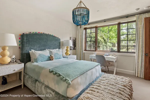 a bedroom with a bed chandelier and a window