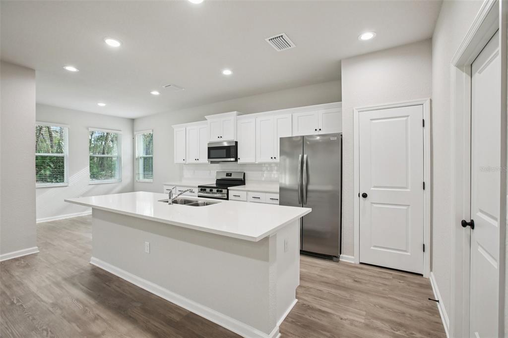 64 Cactus Street Homosassa, FL 34446 - Photo 6 of 12 a kitchen with a refrigerator a sink and white cabinets
