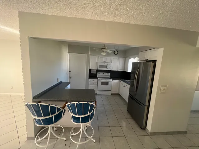 a kitchen with stainless steel appliances kitchen island granite countertop a refrigerator a stove a sink dishwasher and white cabinets with wooden floor