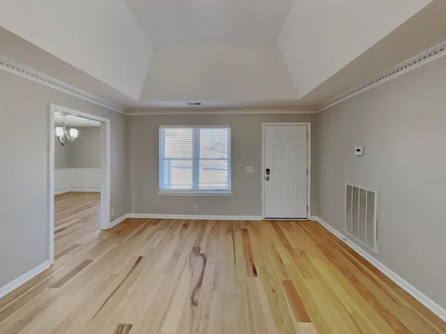 a view of an empty room with wooden floor and a window