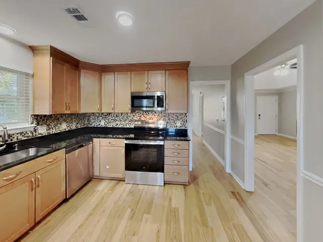 a large kitchen with cabinets wooden floor and stainless steel appliances