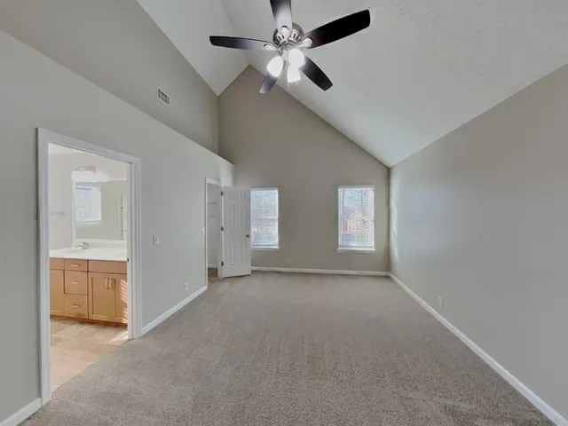 an empty room with chandelier fan and windows