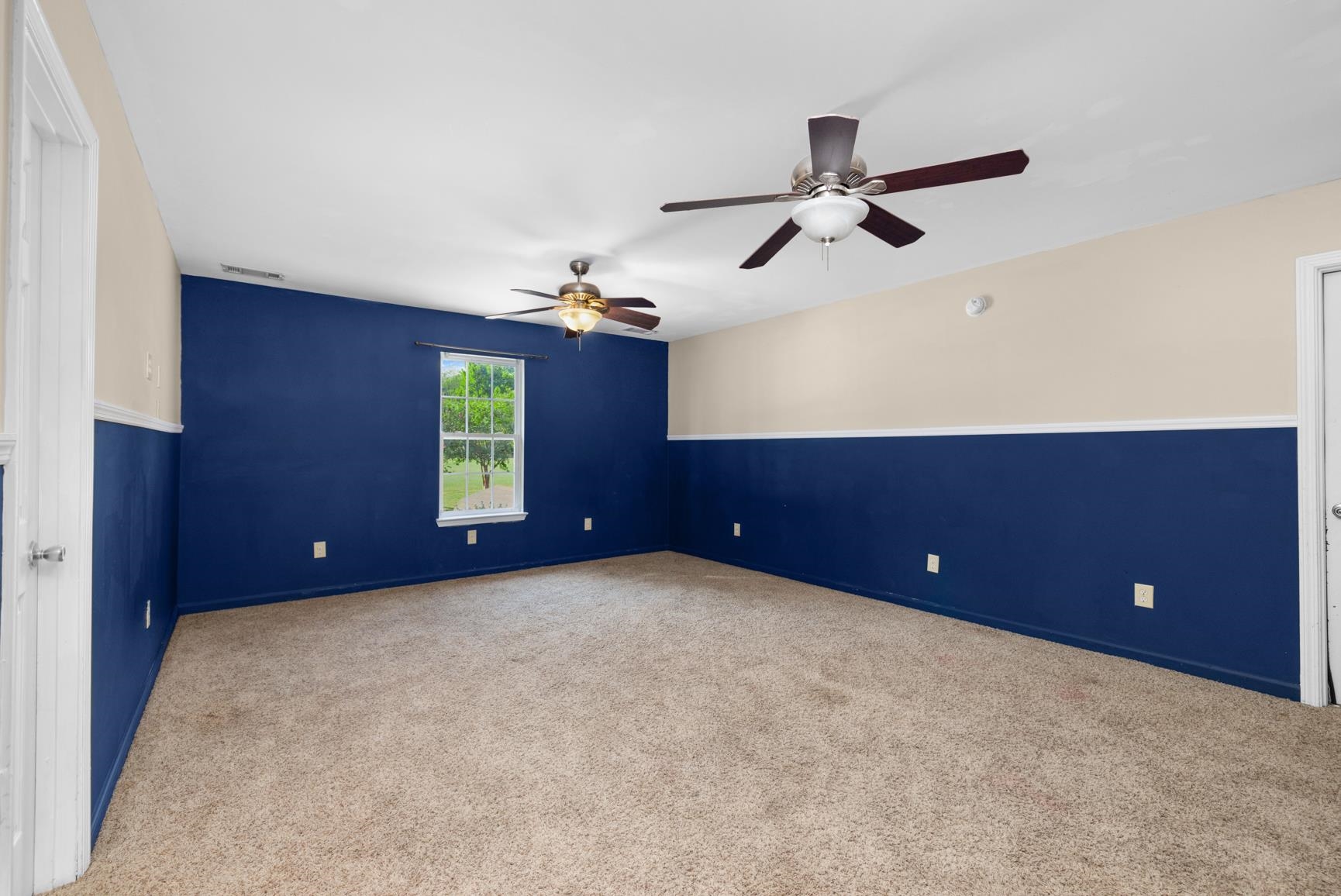420 Sanford Road Covington, TN 38019 - Photo 21 of 27 Carpeted flooring, two ceiling fans with integrated lighting, a window with exterior visibility, and two-tone wall treatment