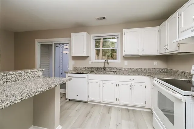 a kitchen with granite countertop white cabinets and white appliances