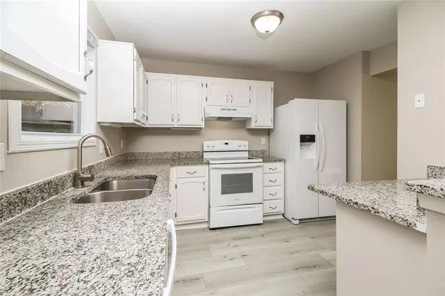a kitchen with granite countertop a sink stove and refrigerator