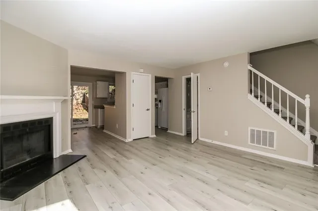 a view of an empty room with wooden floor fireplace and a window