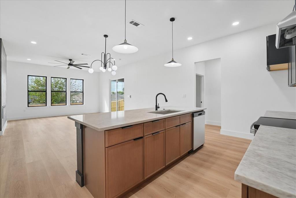 1648 West Wintergreen Road Lancaster, TX 75134 - Photo 5 of 23 Kitchen island with integrated sink, stainless steel dishwasher, and pendant lighting