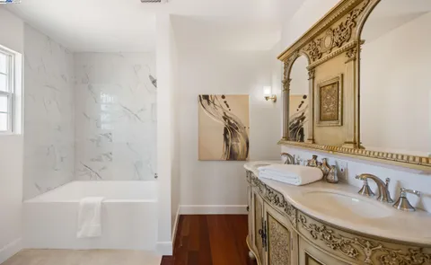 a bathroom with a granite countertop sink a mirror a vanity and a bathtub