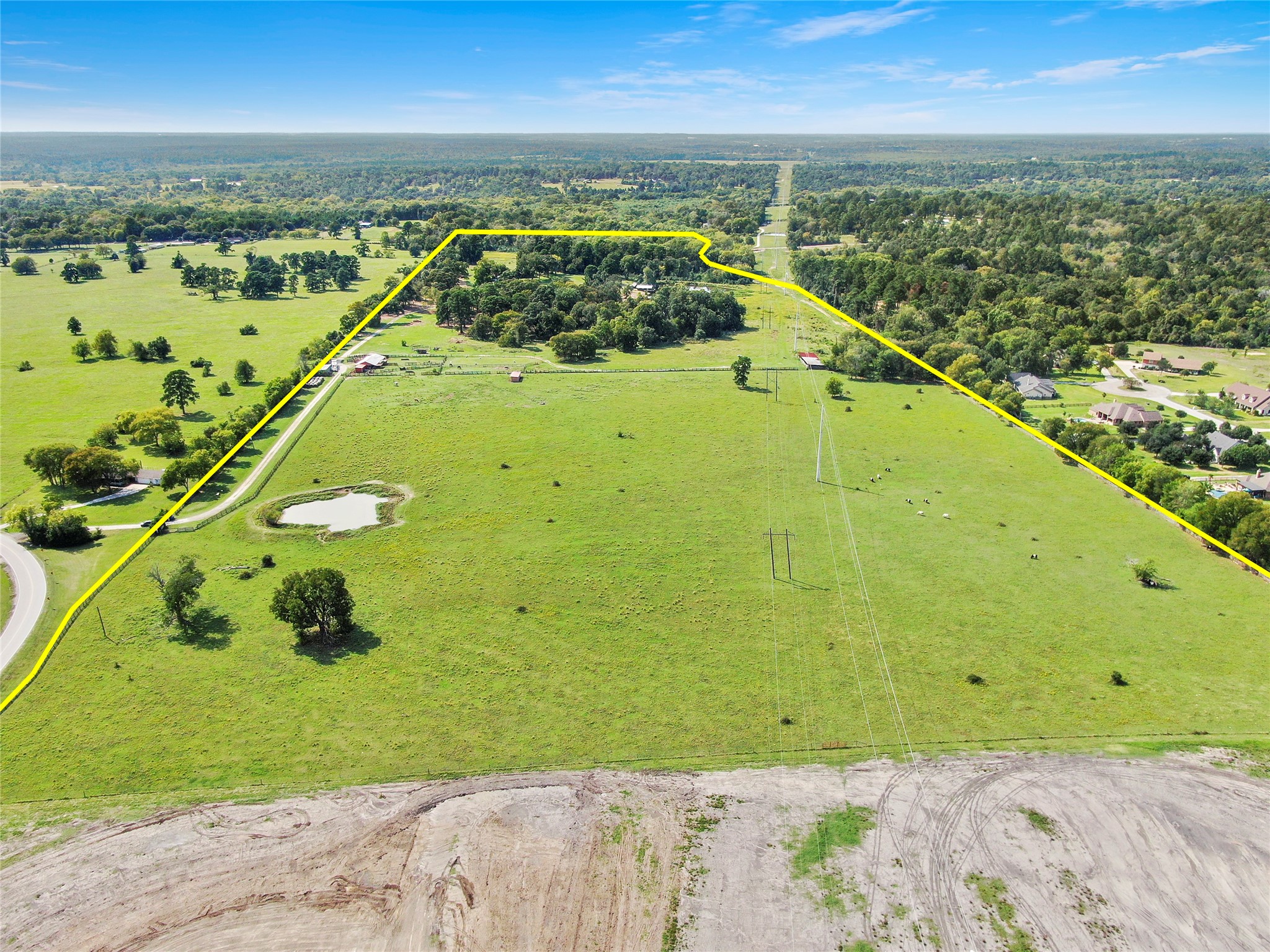 6605 Spring Branch Road Montgomery, TX 77316 - Photo 11 of 12 Stunning aerial perspective of lush green pastures, mature trees, a scenic pond, and improved fencing—all within the 80-acre tract. Prime location with frontage along Spring Branch Rd and utilities nearby.