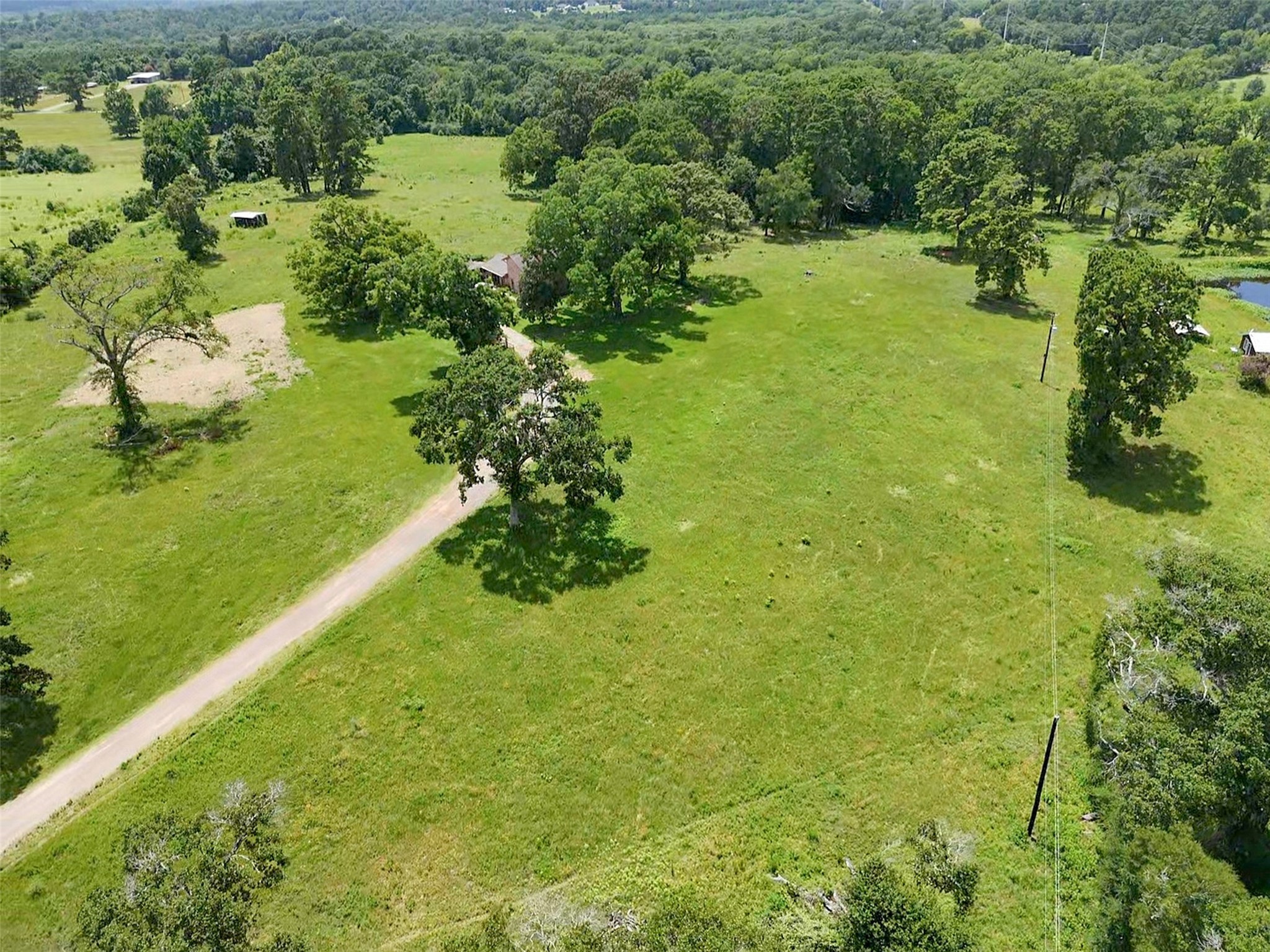 6605 Spring Branch Road Montgomery, TX 77316 - Photo 3 of 12 An aerial perspective captures the property's sweeping layout—rolling pastures, a scattered tree line, and thoughtfully placed outbuildings blend utility and beauty.