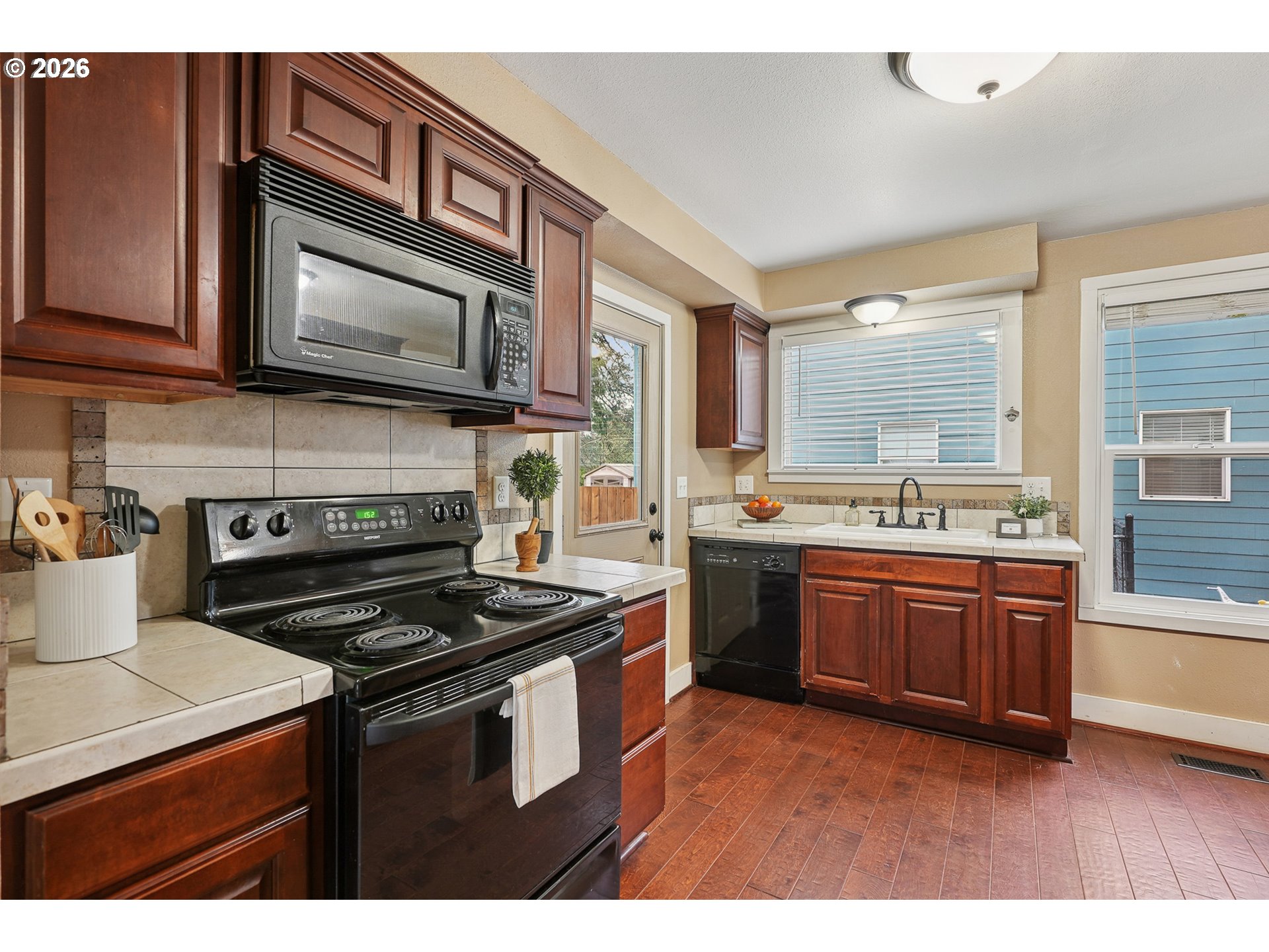 9306 Southwest 30th Avenue Portland, OR 97219 - Photo 10 of 30 a kitchen with stainless steel appliances granite countertop a stove a sink dishwasher and a microwave oven with cabinets
