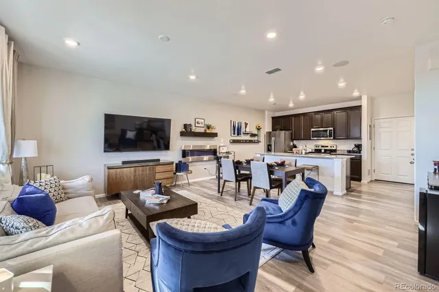 a living room with furniture a flat screen tv and kitchen view