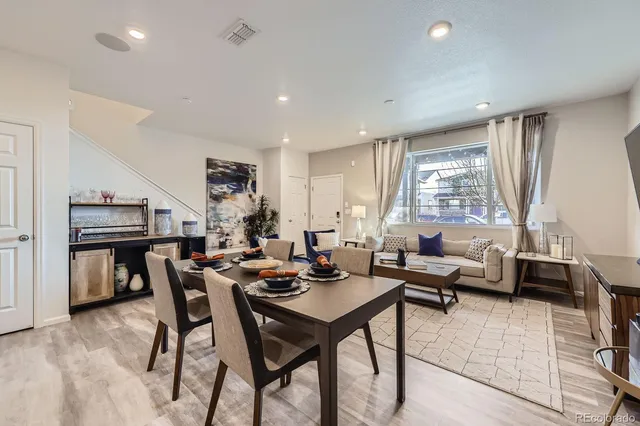 a living room with furniture and a dining table with kitchen appliances
