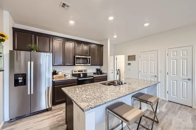 a kitchen with stainless steel appliances granite countertop a refrigerator a stove and a wooden cabinets