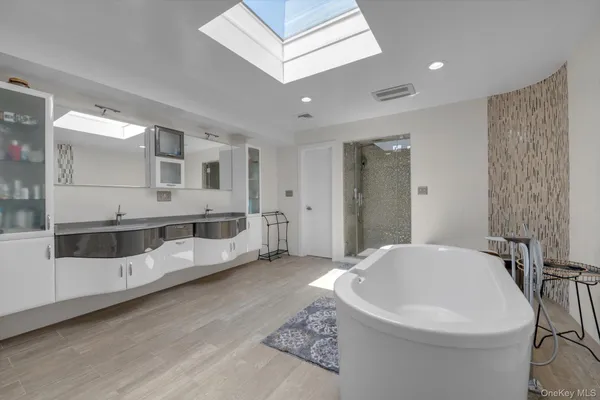 a bathroom with a white tub a mirror and shower