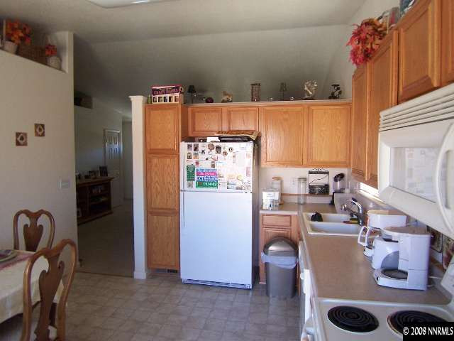 18031 Hazelnut Drive Reno, NV 89508 - Photo 3 of 9 a workspace with kitchen island a refrigerator a stove a sink and a dining table