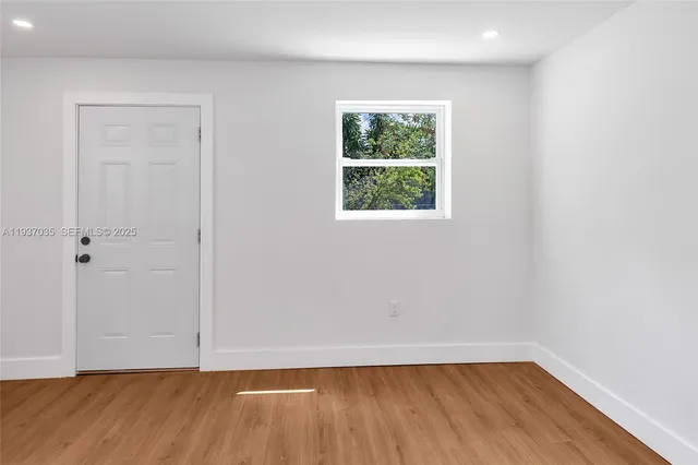 an empty room with wooden floor and window