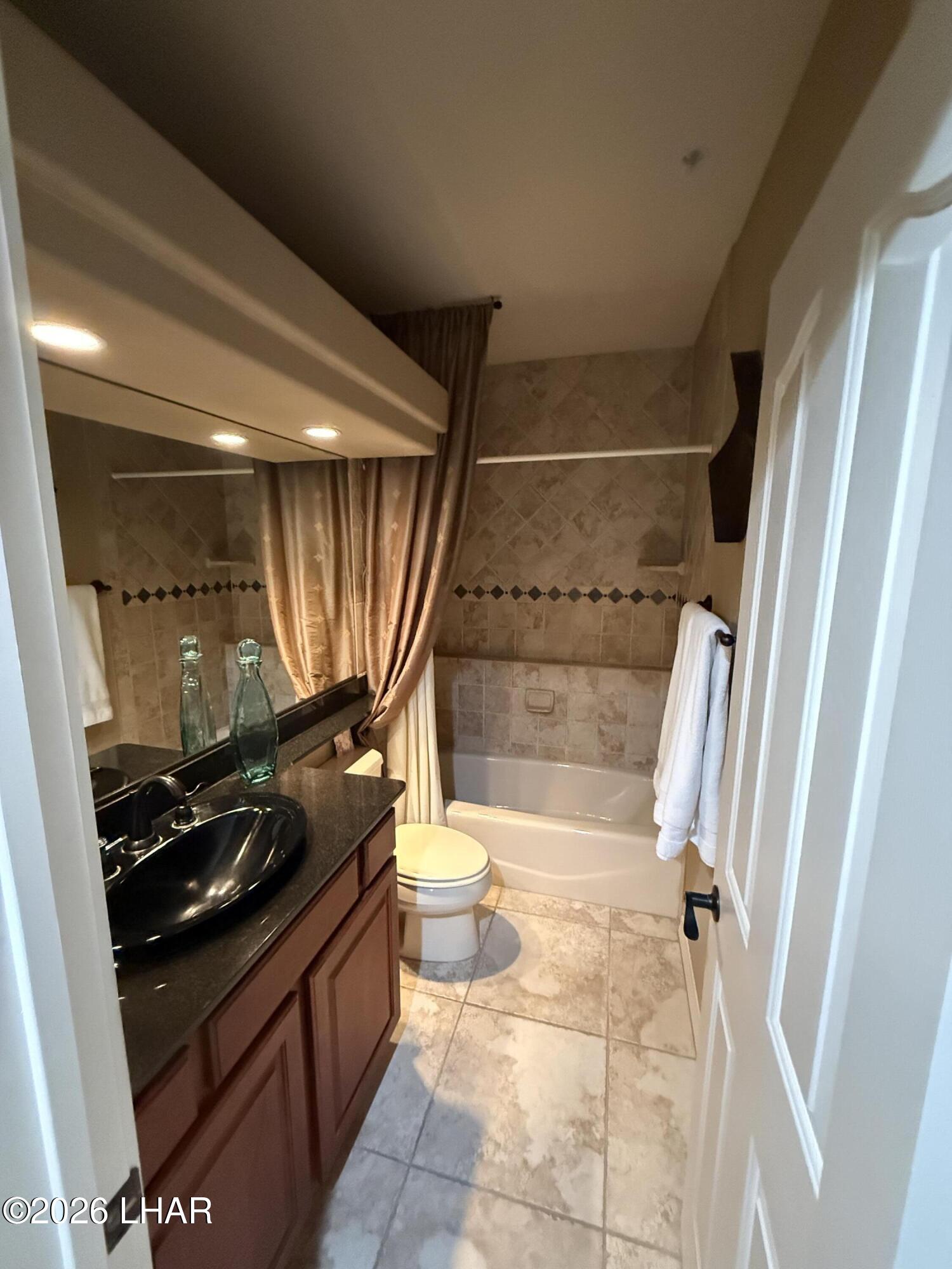 433 London Bridge Road, Unit B101 Lake Havasu City, AZ 86403 - Photo 32 of 35 a bathroom with a granite countertop sink toilet and shower