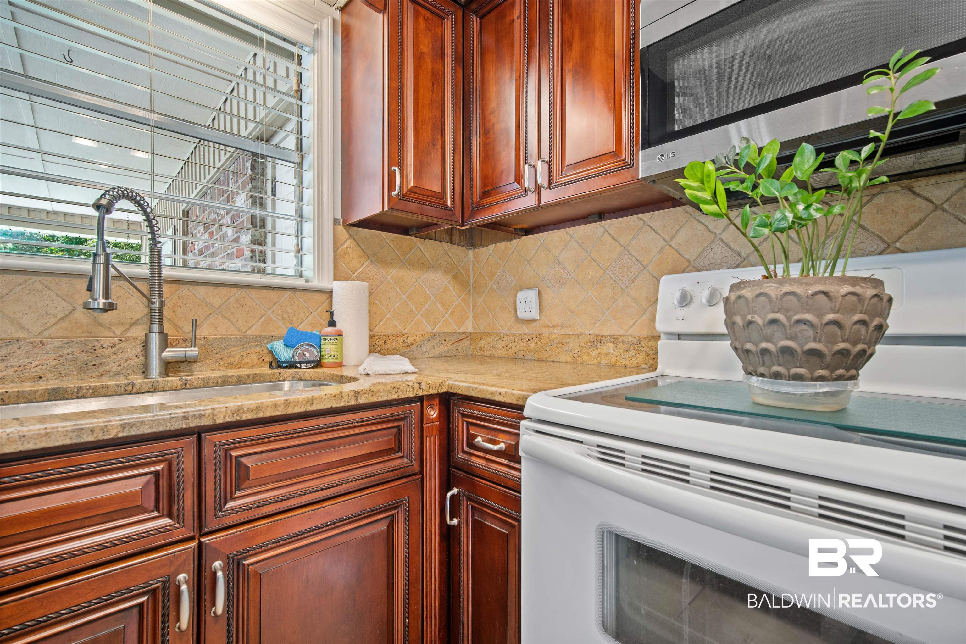 1325 Pawnee Circle Saraland, AL 36571 - Photo 11 of 26 Kitchen featuring white electric stove, stainless steel microwave, backsplash, and light stone counters