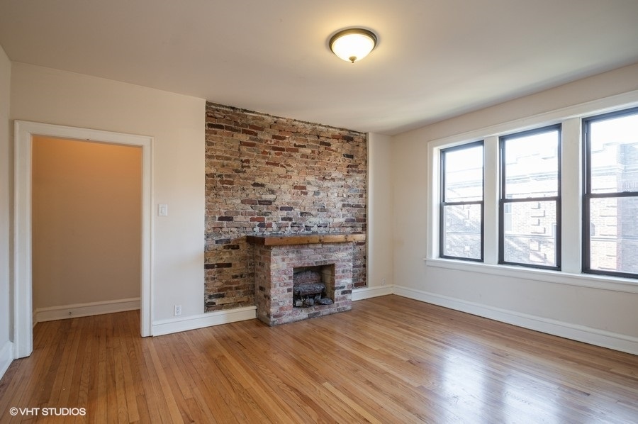 Undisclosed Address Chicago, IL 60657 - Photo 4 of 7 an empty room with windows a fireplace and wooden floor