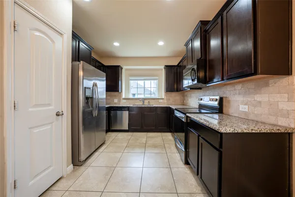 a view of a refrigerator in kitchen and an empty room