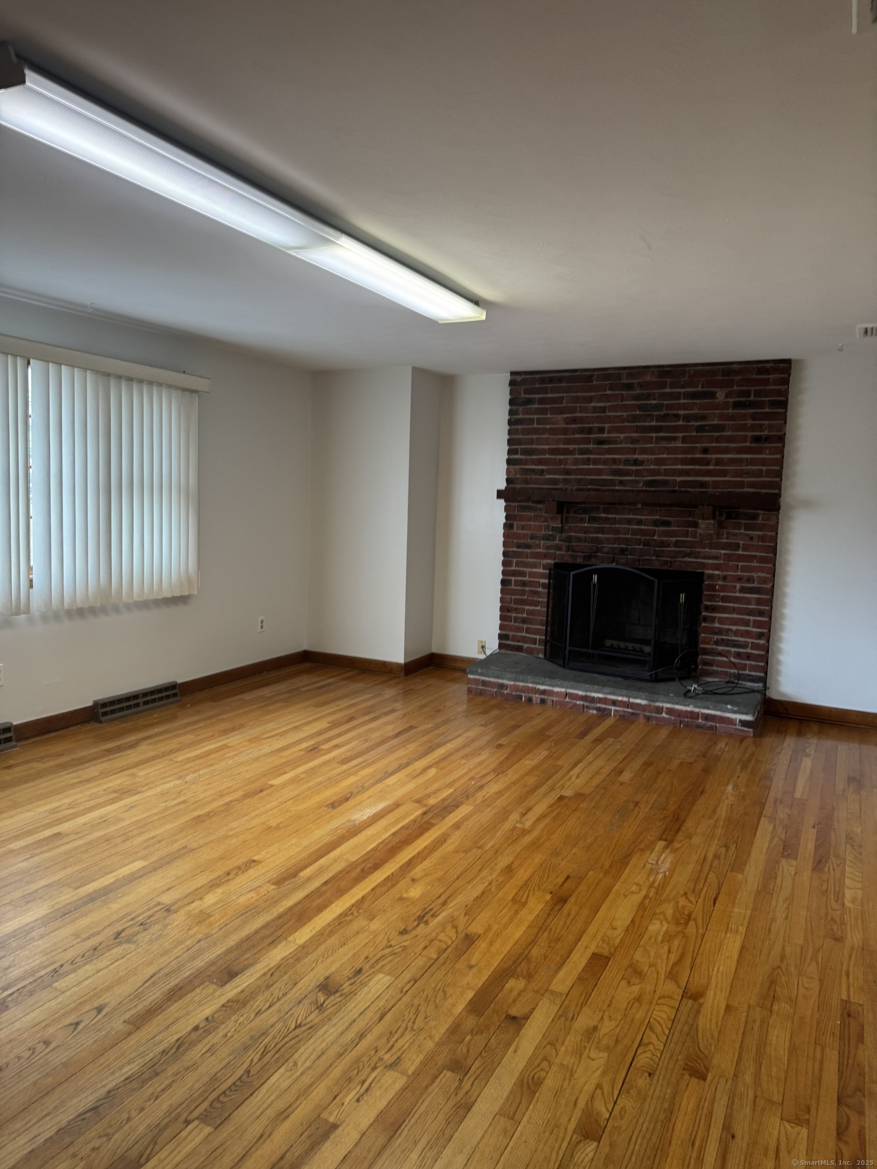 an empty room with wooden floor and fireplace