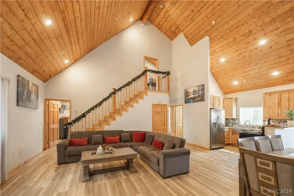 a living room with couches and kitchen view with wooden floor