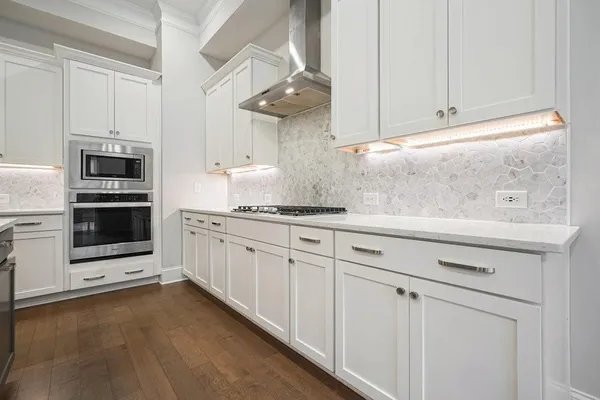 an open kitchen with wooden floor and stainless steel appliances