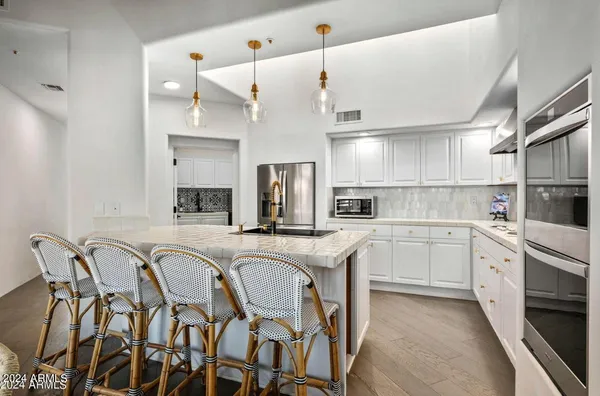 a kitchen with stainless steel appliances granite countertop a table chairs sink and cabinets