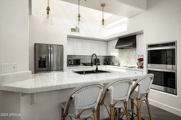 a kitchen with stainless steel appliances granite countertop a sink a stove and a refrigerator