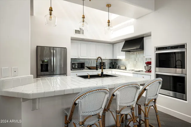 a kitchen with stainless steel appliances granite countertop a sink a stove and a refrigerator
