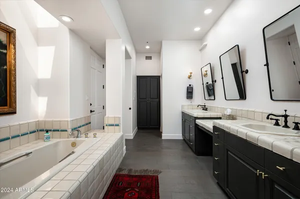 a spacious bathroom with a bathtub sink double vanity and mirror